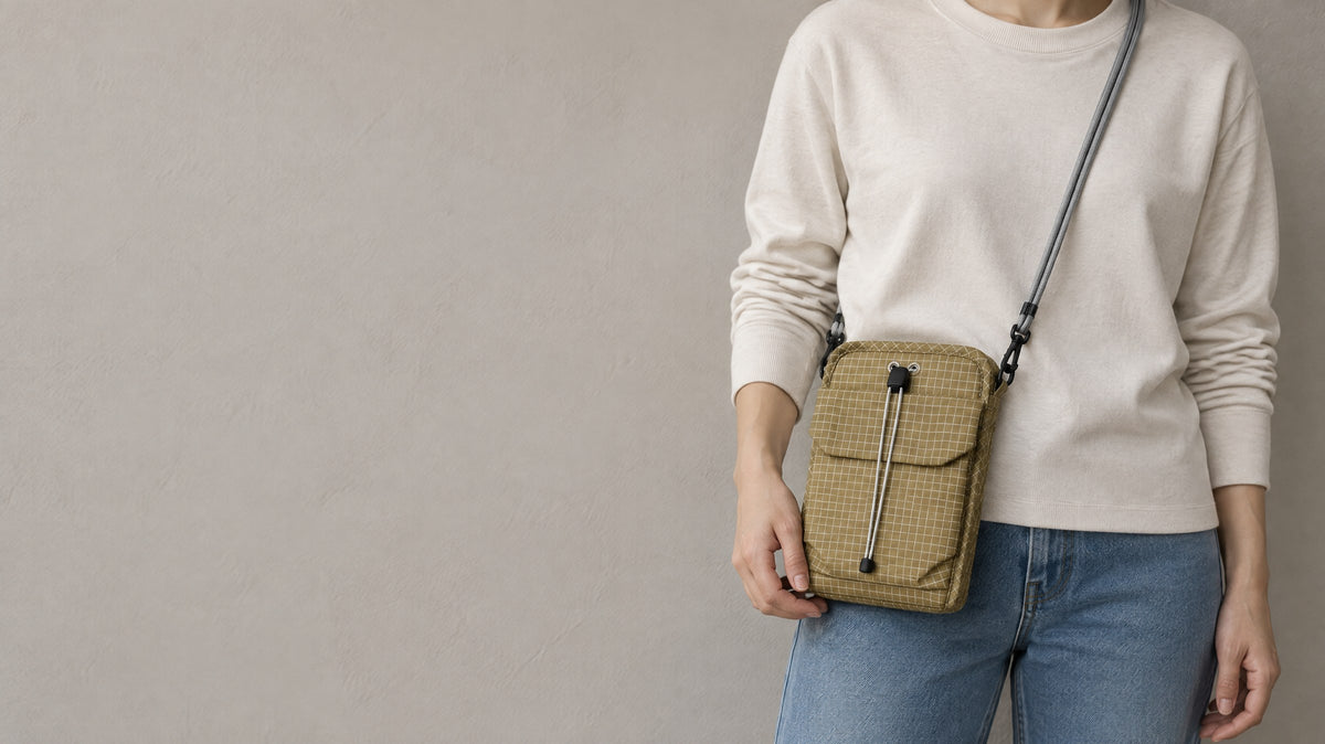 Organizer crossbody bag in Tan worn across the body against a plain wall